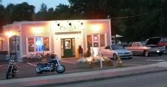 Hartford Road Pizza lit up at night with motorcycles and cars parked out front