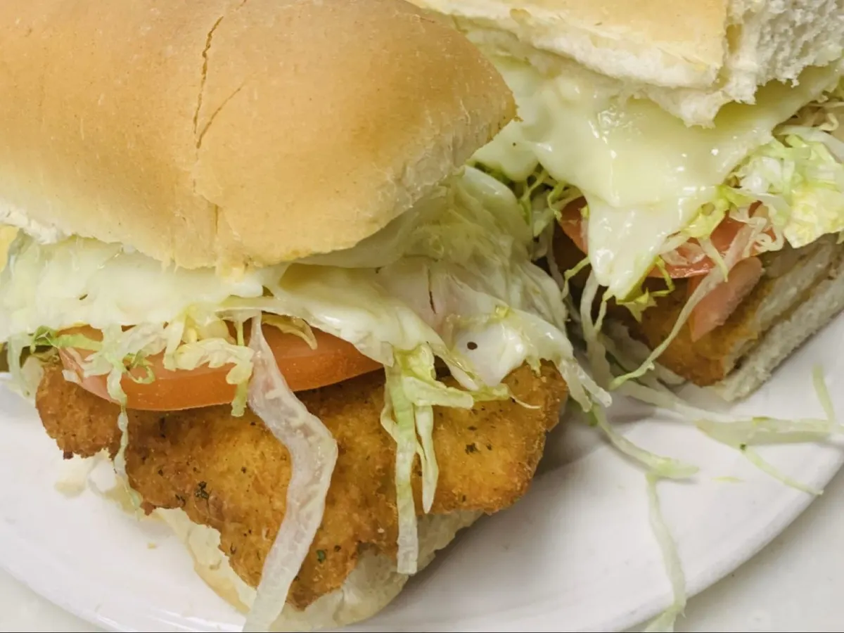 Chicken cutlet grinder on a long roll with melted cheese, lettuce and tomato
